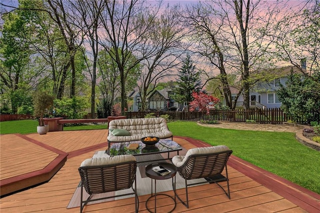 deck at dusk featuring an outdoor living space, a yard, and a fenced backyard