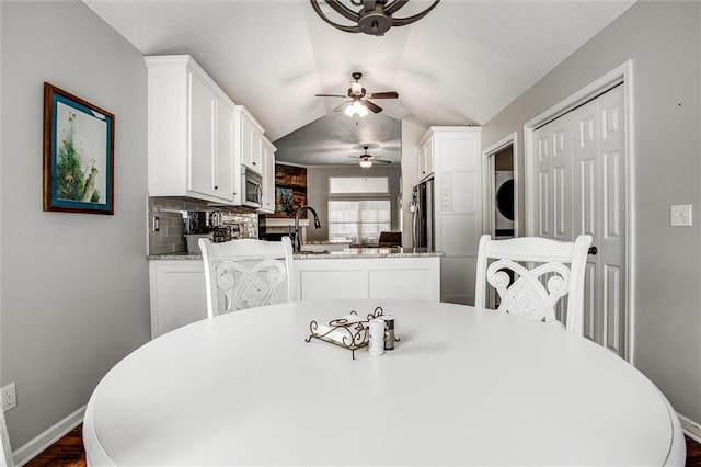 3204 SW Alice Ln, Lees Summit, MO 64082 - dining room featuring ceiling fan, stacked washer and dryer, vaulted ceiling, baseboards, and dark wood-style floors