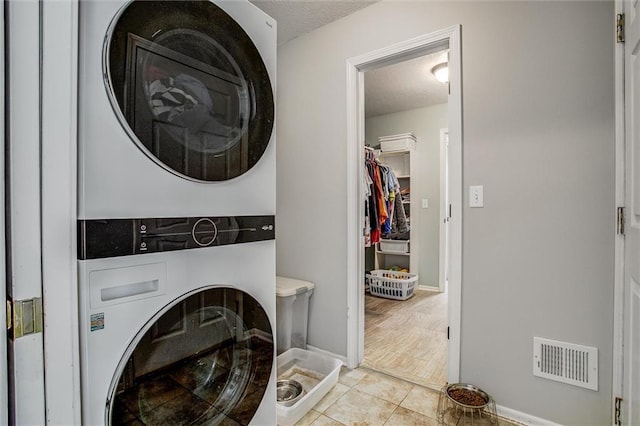 3204 SW Alice Ln, Lees Summit, MO 64082 - washroom featuring stacked washer and dryer, laundry area, tile patterned flooring, a textured ceiling, and visible vents