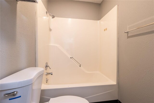 full bathroom with a textured wall, toilet, and bathtub / shower combination