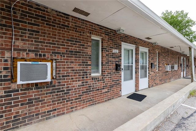 view of exterior entry featuring brick siding and visible vents