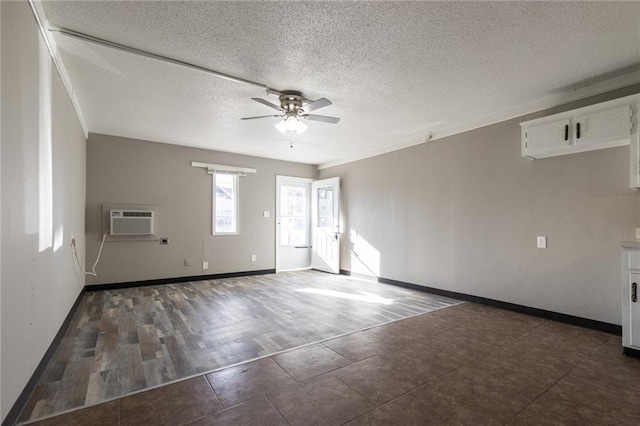unfurnished room featuring a ceiling fan, a wall unit AC, a textured ceiling, and baseboards