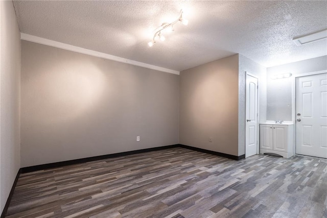 interior space featuring a textured ceiling, wood finished floors, and baseboards