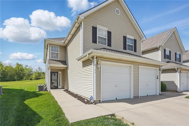 traditional-style home featuring an attached garage, central air condition unit, driveway, and a front lawn