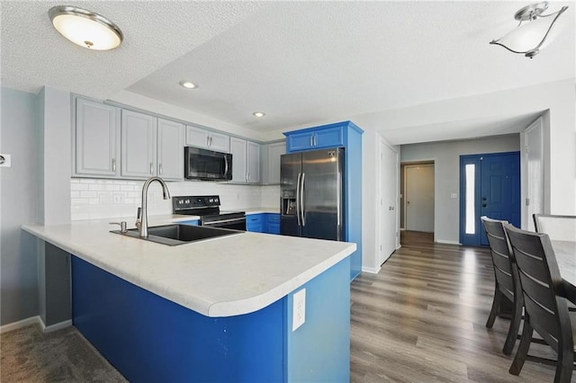 kitchen with stainless steel appliances, a sink, a peninsula, light countertops, and a textured ceiling