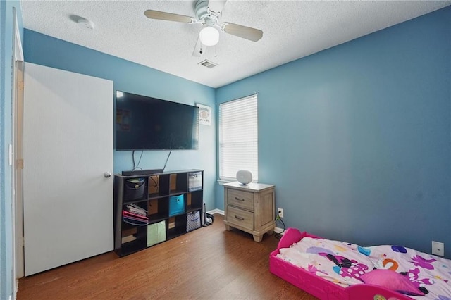 bedroom featuring wood finished floors, a textured ceiling, and a ceiling fan