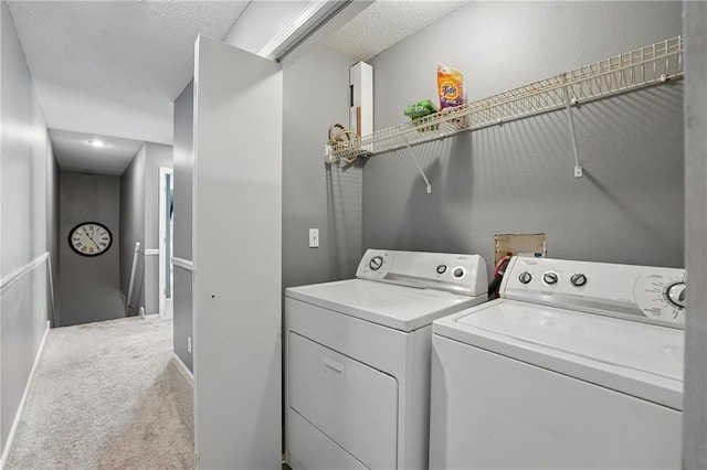 laundry area with washer and clothes dryer, light colored carpet, and a textured ceiling