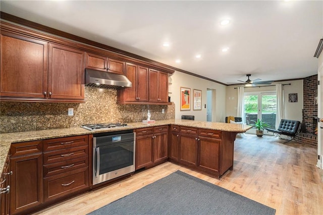 kitchen featuring ornamental molding, a peninsula, oven, light wood-style floors, and under cabinet range hood