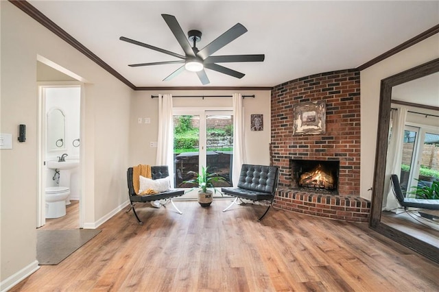 sitting room featuring baseboards, ornamental molding, a fireplace, and wood finished floors