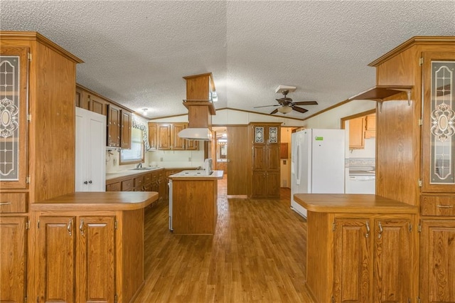 20 SE E Hwy, Trenton, MO 64683 - kitchen featuring wood finished floors, brown cabinets, white appliances, a peninsula, and ornamental molding