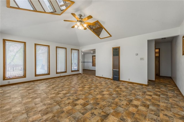 20 SE E Hwy, Trenton, MO 64683 - unfurnished living room featuring baseboards, stone finish floor, lofted ceiling with skylight, and ceiling fan