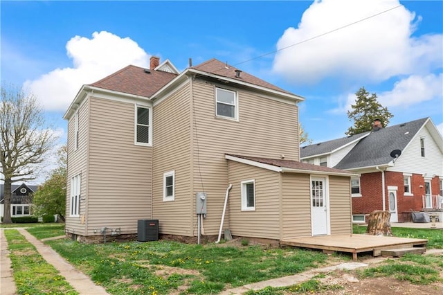 1404 Main St, Higginsville, MO 64037 - back of house with a deck, central AC, and a lawn