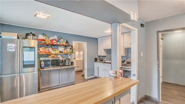 812 Pacific Ave, Osawatomie, KS 66064 - kitchen with appliances with stainless steel finishes, light countertops, light wood-type flooring, and open shelves
