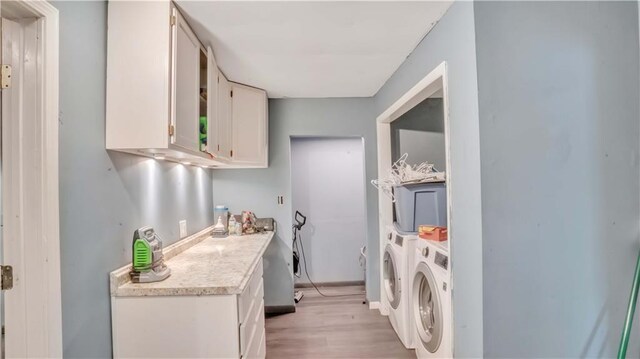 812 Pacific Ave, Osawatomie, KS 66064 - laundry area with washer and clothes dryer, light wood finished floors, and cabinet space