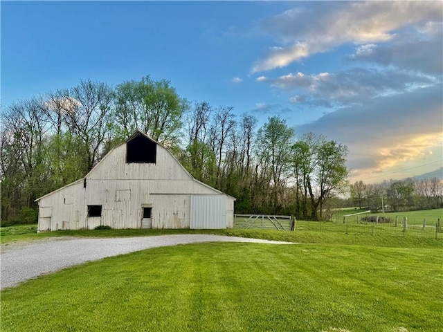 view of barn with fence and a lawn