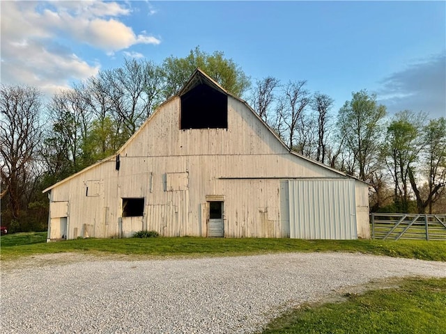 view of barn featuring fence and gravel driveway