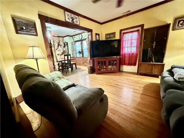 living room featuring crown molding, visible vents, ceiling fan, and wood finished floors