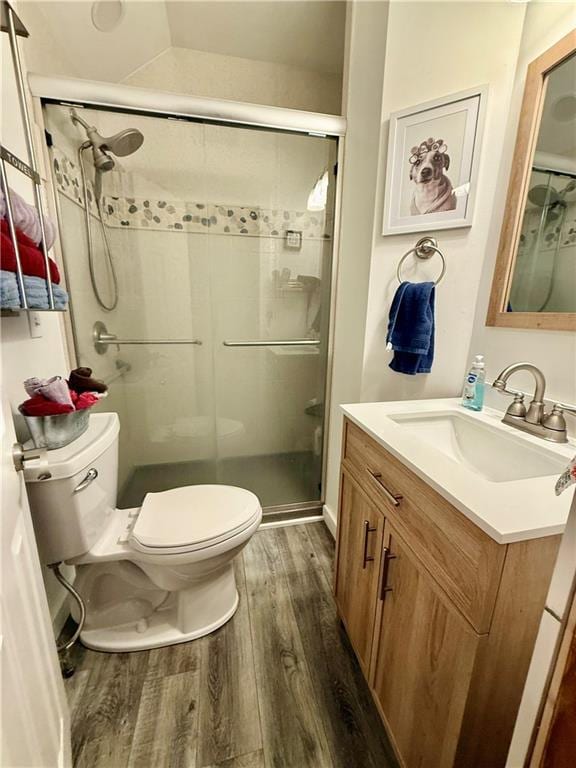 full bathroom with wood finished floors, a shower stall, toilet, and vanity