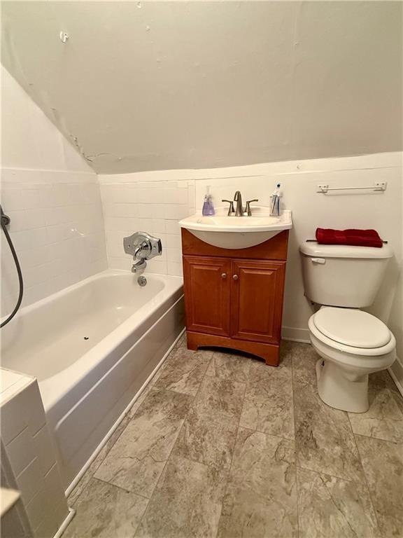 bathroom featuring a tub to relax in, toilet, and vanity