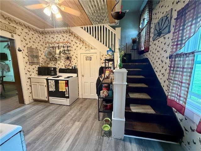staircase featuring a ceiling fan, wallpapered walls, and wood finished floors