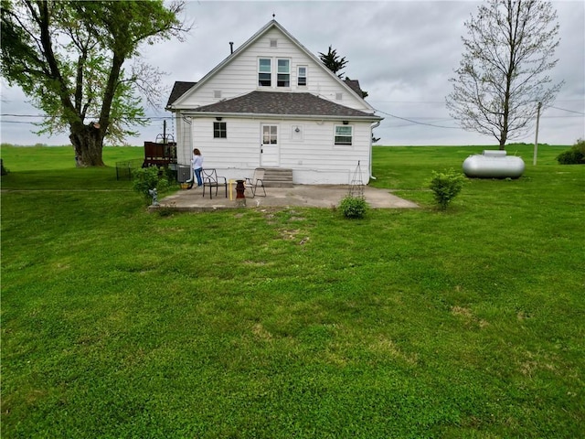 back of property featuring a yard, a shingled roof, and a patio area