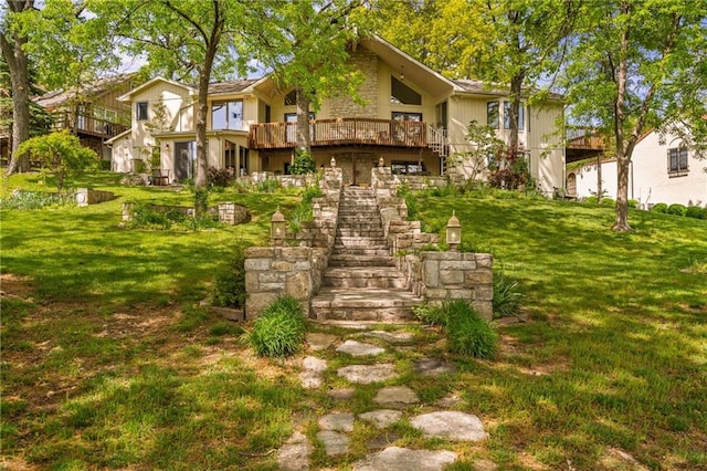 back of property with stairs, a deck, and a lawn