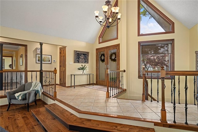 tiled entryway featuring a chandelier, baseboards, and high vaulted ceiling