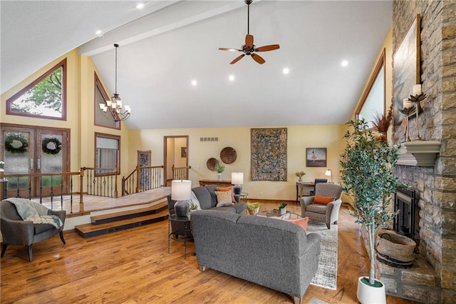 living area with high vaulted ceiling, a stone fireplace, ceiling fan, beam ceiling, and a chandelier