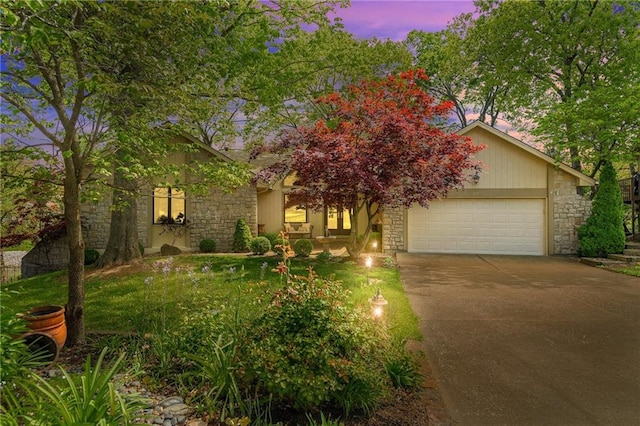 view of property hidden behind natural elements with stone siding, driveway, a garage, and a front yard