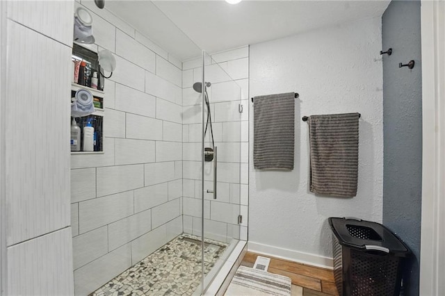 bathroom with baseboards, a textured wall, and a stall shower