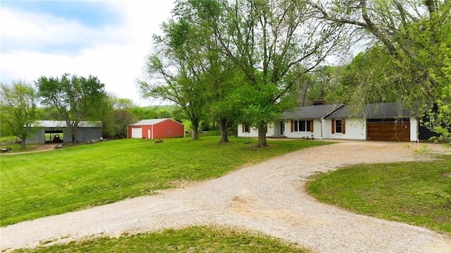 ranch-style home featuring curved driveway, a chimney, and a front yard