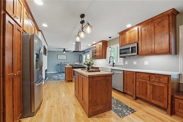 kitchen featuring ceiling fan, a sink, light wood-style floors, brown cabinetry, and stainless steel appliances