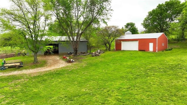 view of yard featuring fence, a pole building, a garage, an outdoor structure, and driveway