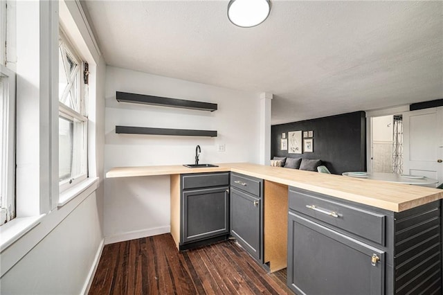 525 W 38th St, Kansas City, MO 64111 - kitchen with gray cabinets, wooden counters, dark wood-type flooring, a sink, and baseboards