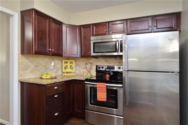 464 W 104th St Unit A, Kansas City, MO 64114 - kitchen with dark brown cabinets, baseboards, decorative backsplash, light stone counters, and appliances with stainless steel finishes