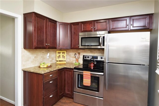 464 W 104th St Unit A, Kansas City, MO 64114 - kitchen with tasteful backsplash, light stone countertops, reddish brown cabinets, and stainless steel appliances