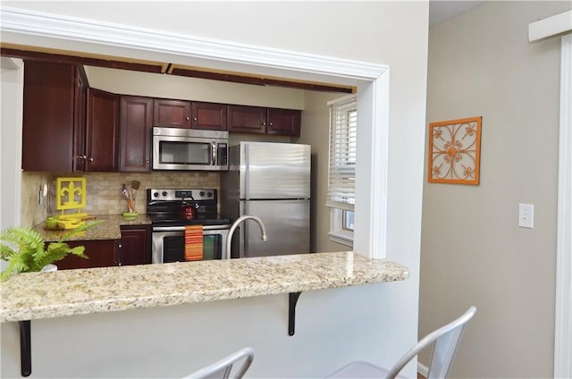 464 W 104th St Unit A, Kansas City, MO 64114 - kitchen featuring stainless steel appliances, a kitchen bar, light stone counters, and tasteful backsplash