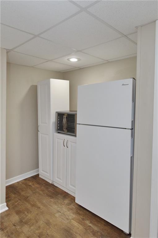 464 W 104th St Unit A, Kansas City, MO 64114 - kitchen with wood finished floors, baseboards, a paneled ceiling, and freestanding refrigerator