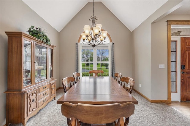 dining space featuring light carpet, vaulted ceiling, baseboards, and an inviting chandelier