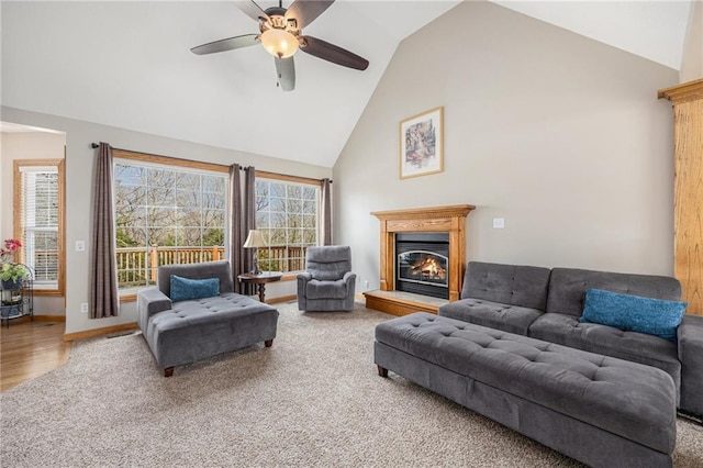 living area with a glass covered fireplace, carpet flooring, high vaulted ceiling, and ceiling fan