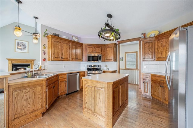 kitchen with light wood finished floors, a center island, a sink, and appliances with stainless steel finishes