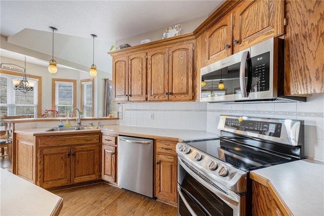 kitchen featuring light countertops, brown cabinetry, appliances with stainless steel finishes, and a sink