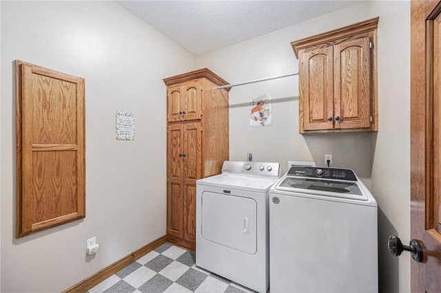 washroom featuring light floors, washing machine and clothes dryer, baseboards, cabinet space, and a textured ceiling