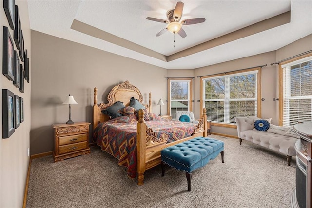 carpeted bedroom with ceiling fan, baseboards, access to outside, and a raised ceiling