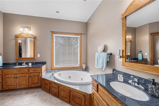 full bath with two vanities, a sink, and a jetted tub