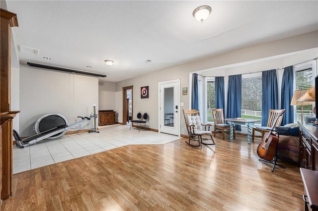 living area featuring a wealth of natural light, light wood-style floors, visible vents, and baseboards