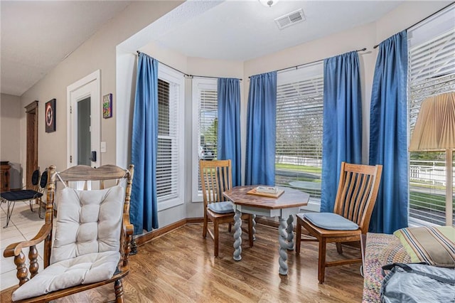 living area with baseboards, wood finished floors, and visible vents