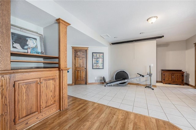 workout room with baseboards and light tile patterned floors