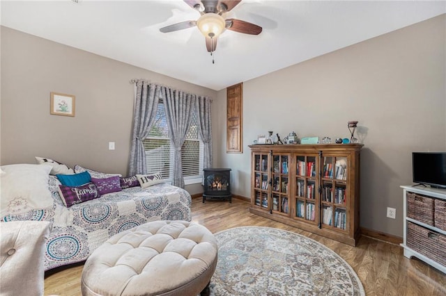 bedroom with baseboards, wood finished floors, and a wood stove