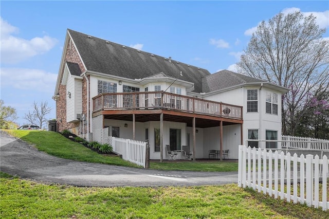 back of property with a yard, fence, and a deck
